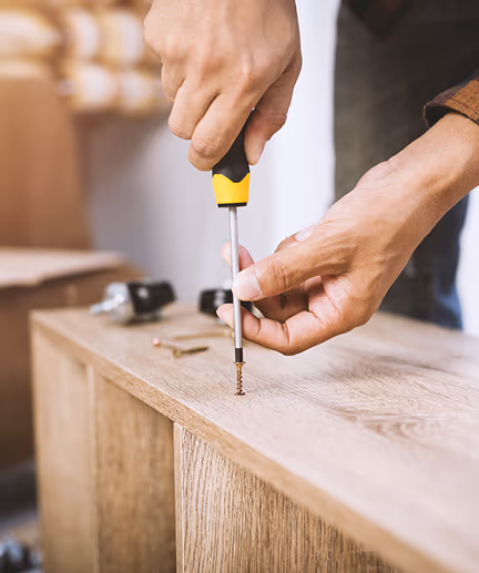 Möbelstück wird mit Hilfe von Schrauben mittels Kreuz-Schraubendreher montiert.